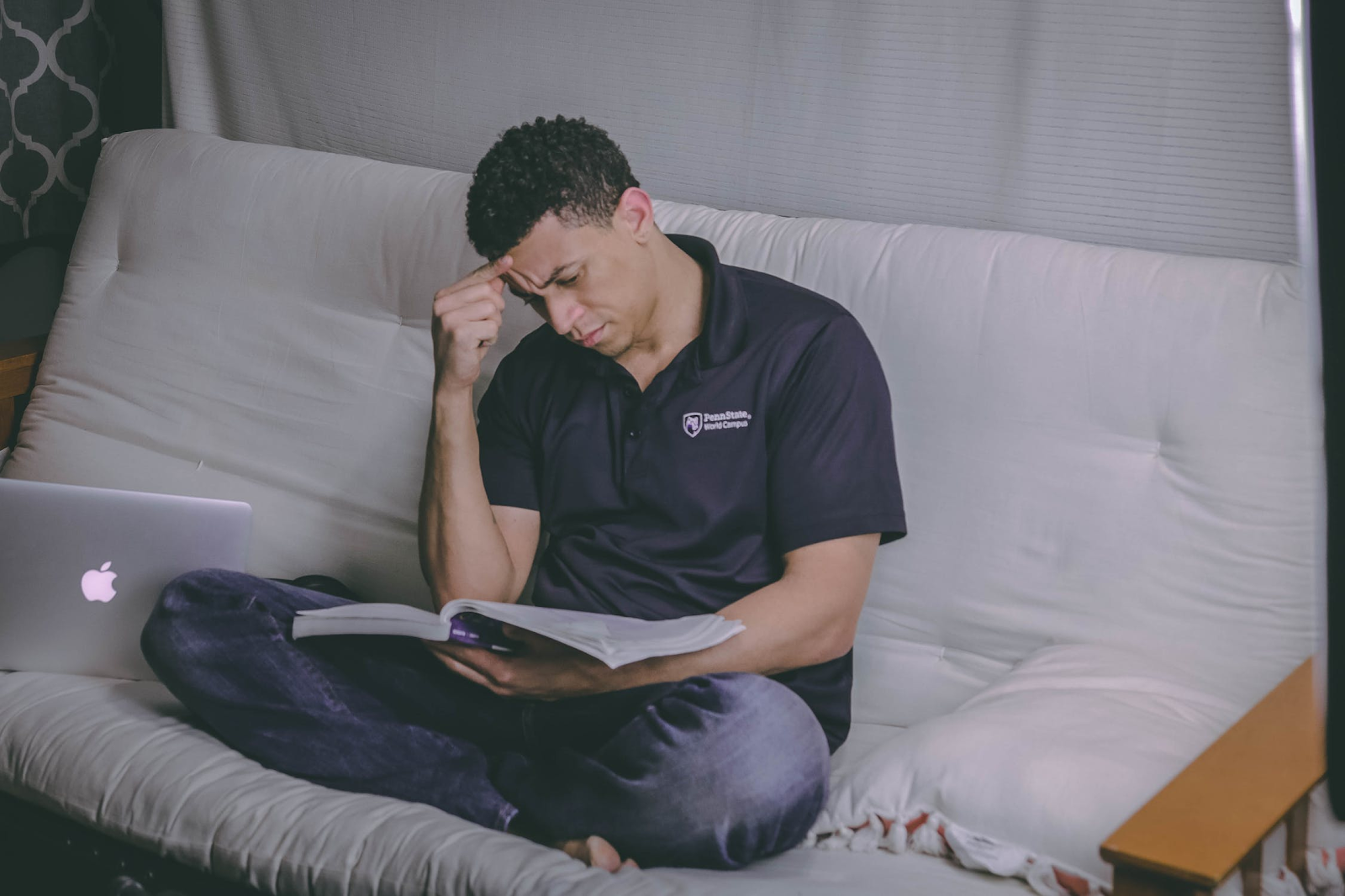 Student reading text book on sofa