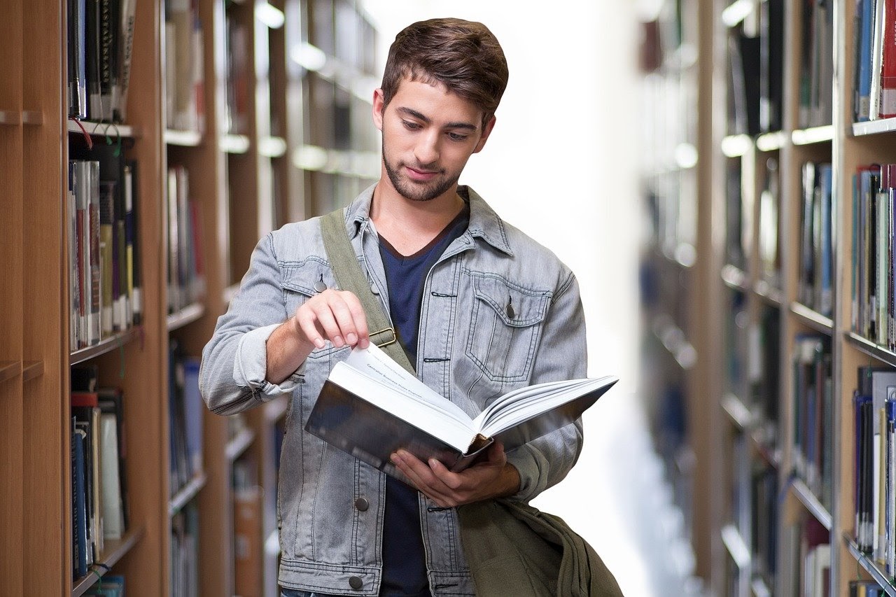 young man in library reading a book