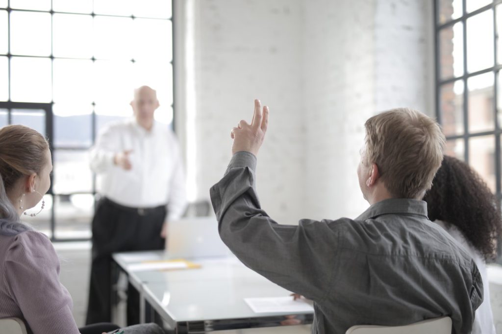 student with hand up in class