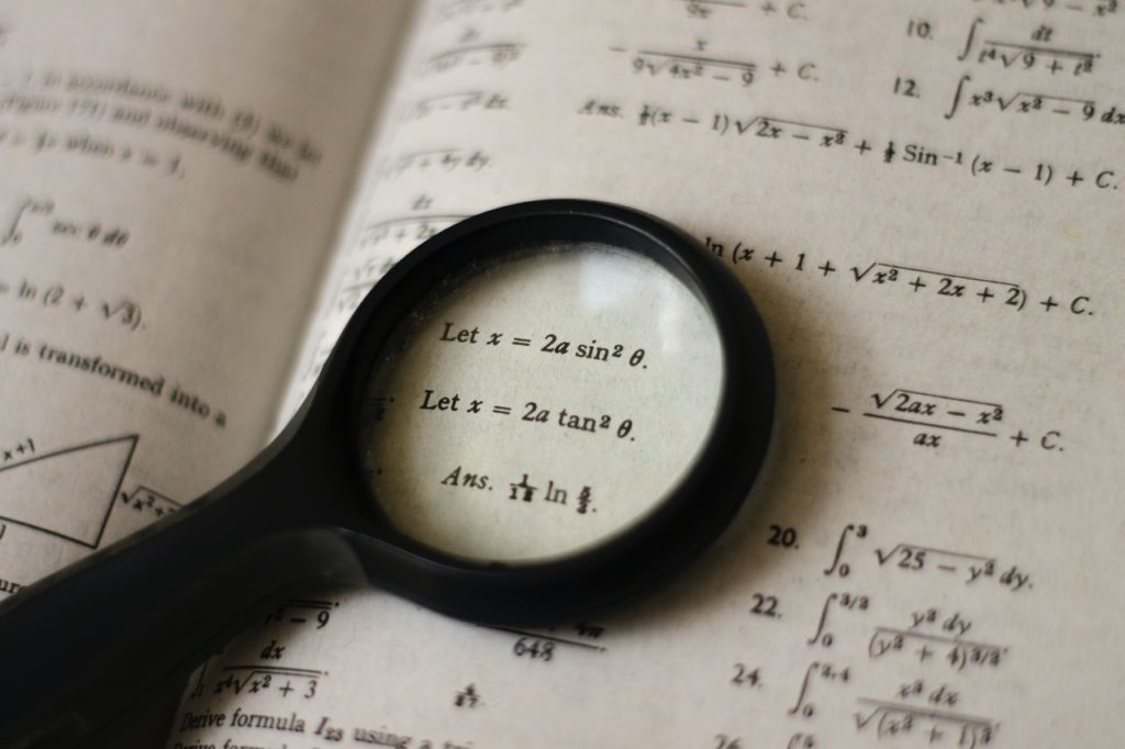 Equations in book with magnifying glass