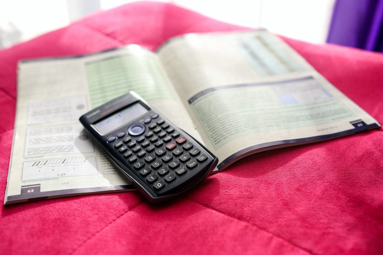 calculator and maths book on pink rug