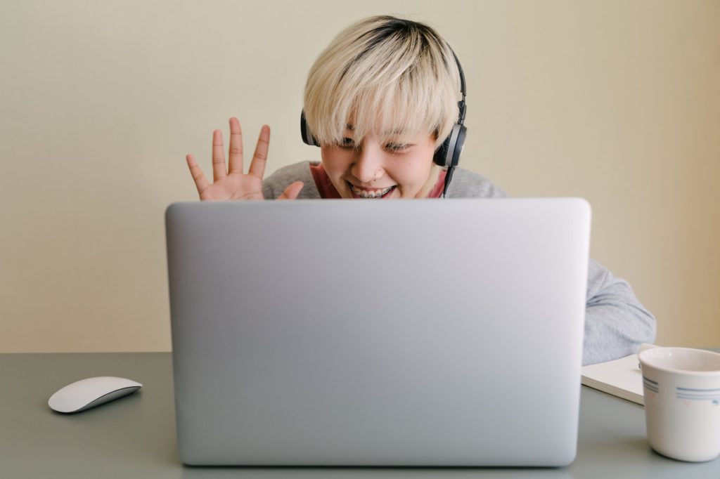 Student waving at laptop screen 