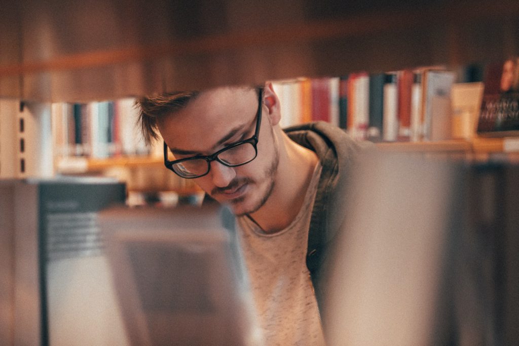 Man looking through book at library