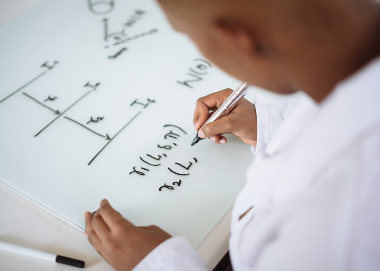 Woman using white board for equations