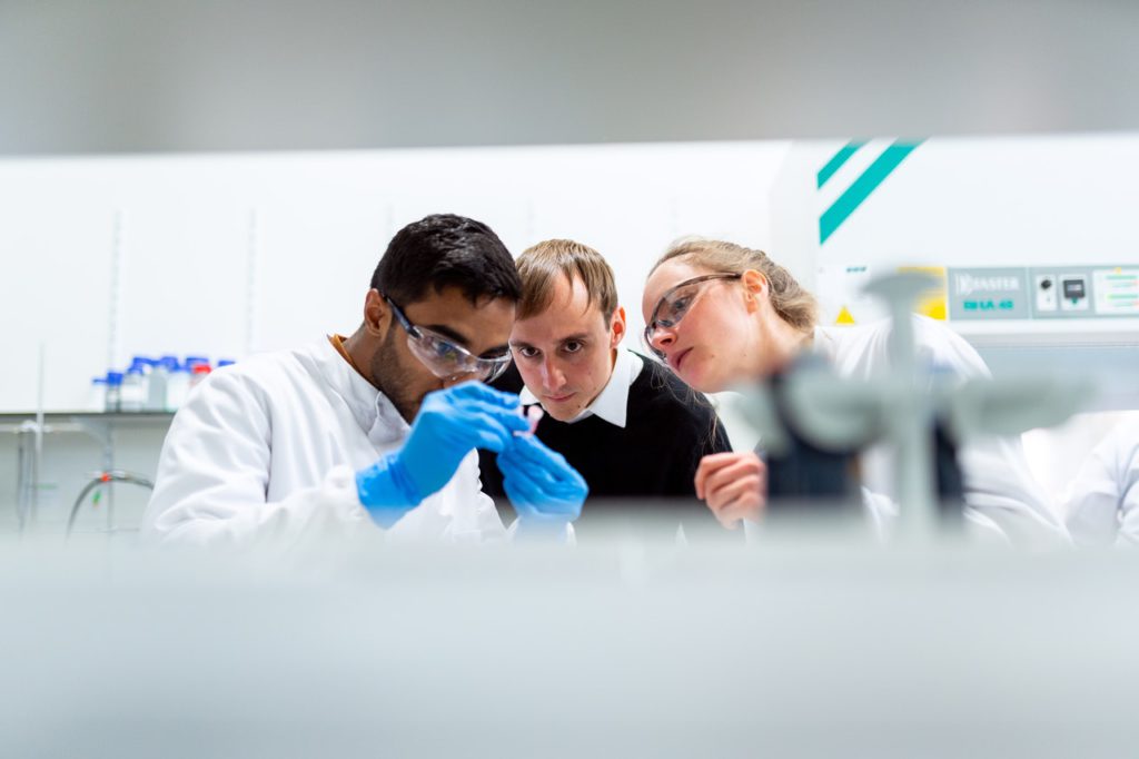 three lab assistant looking at sample