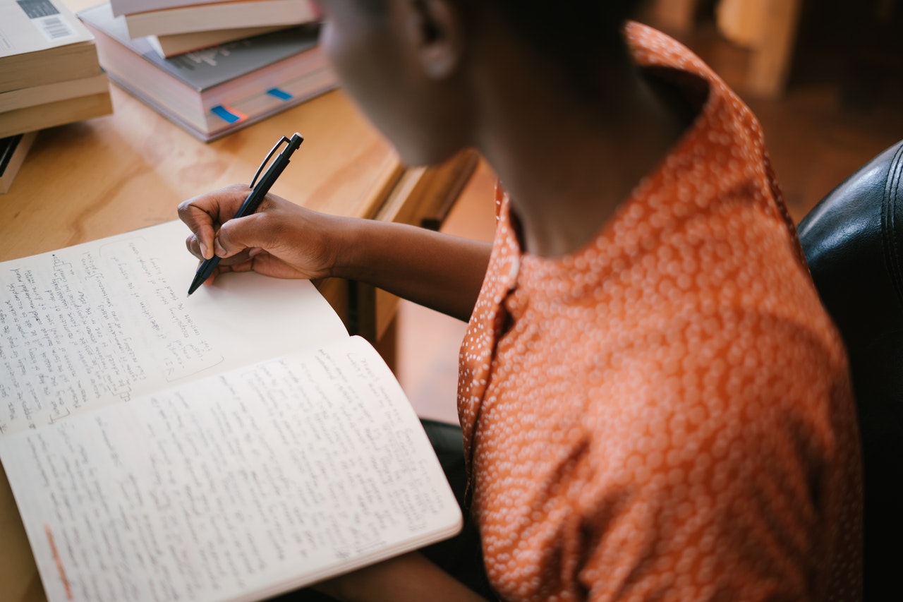 girl writing notes on book